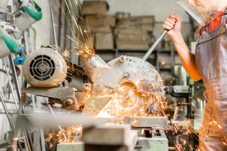 A worker operating a cutting machine, creating sparks.